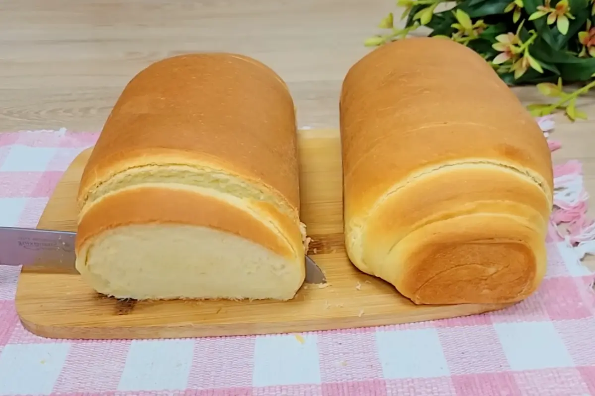 Pão caseiro recém-assado, dourado e macio, em uma tábua de madeira
